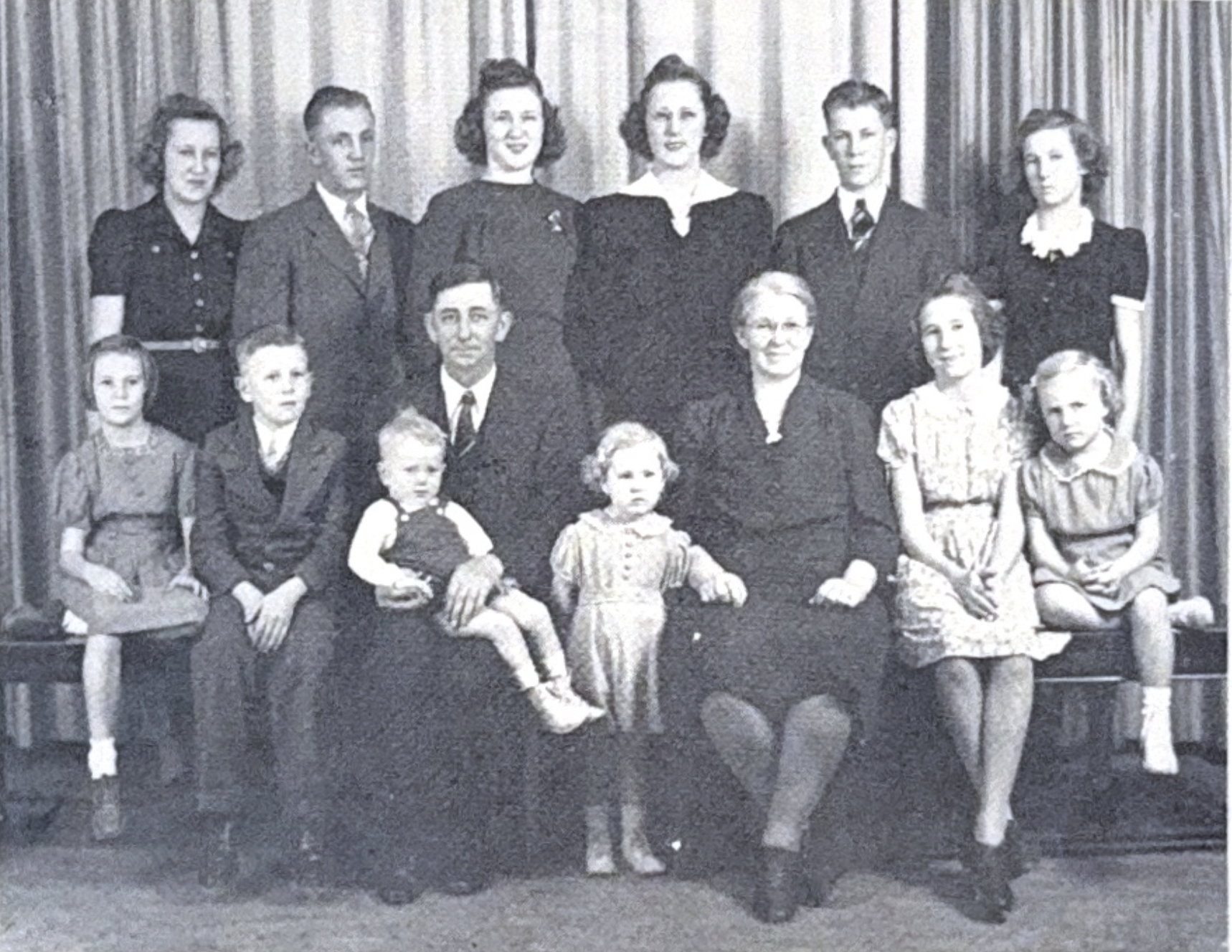 Large family portrait with multiple adults and children arranged in rows